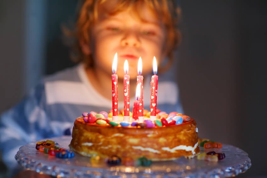 Child smiling behind a birthday cake with lit candles