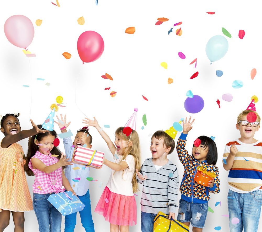 Group of children celebrating at a birthday party with confetti and gifts